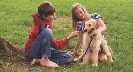 Photograph of two people petting a dog