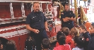 Photograph of two firefighters speaking to a group of students