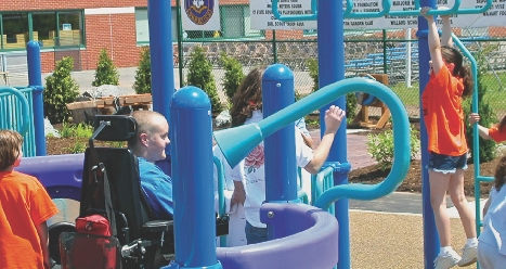 Matt watches children play on equipment that he helped design for Boundless Playgrounds.