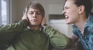 Photo of one person shouting at another, who has hands over his ears, not listening