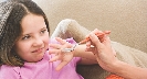 Photograph of a girl with a hand in front of her mouth as food is offered