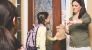 Photograph of a woman handing a girl her lunch in a paper bag