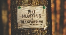 Photograph of a “no hunting/trespassing” sign nailed to a tree