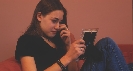 Photograph of a teenager wiping away a tear as she looks at a picture