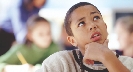 Photograph of a boy thinking about something (holds chin with hand and looks upward)