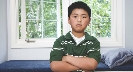 Photograph of a boy standing with his arms crossed