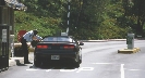 Photograph of a car at a security gate with a security guard