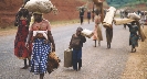 Photograph of refugees walking along a road, carrying their possessions