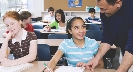 Photograph of a teacher at a student's desk explaining something