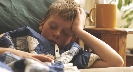 Photograph of a boy laying on a couch with a thermometer in his mouth