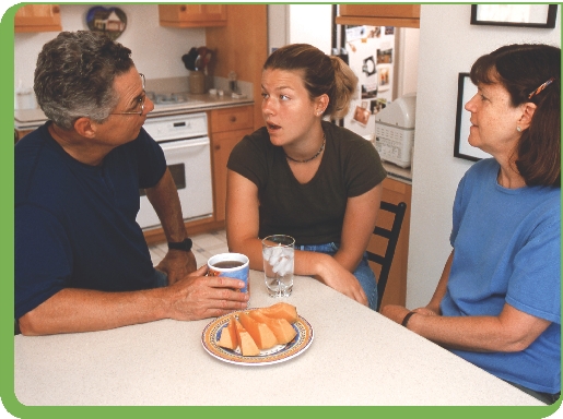 Photograph of a teenage girl with her parents talking at a kitchen table