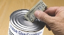 Photograph of someone placing money in a donation can