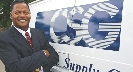 Photograph of a male adult standing next to a company logo