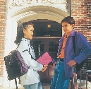 Photograph of a boy and girl with backpacks by a school entrance