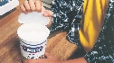 Photograph of a lid being lifted from a yogurt container