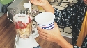 Photograph of yogurt being spooned into a blender