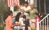 Photograph of people greeting other people on the outside steps of a house