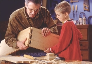 Photograph of a man and a boy building something with wood