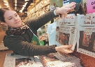 Photograph of a woman with newspapers at a store