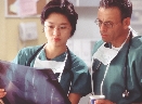 Photograph of two people wearing surgical gowns and masks