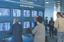 People look at their flight numbers in an airport.