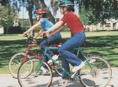 Photograph of two young people with helmets riding bicycles