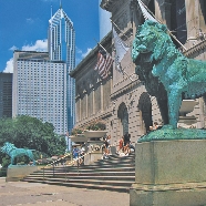 Photograph of two bronze lions at the bottom of the steps of a museum. A U.S. flag hangs near the entrance.