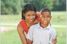 Photograph of a smiling woman standing behind a smiling boy