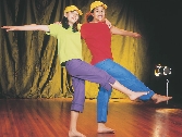 Photograph of two girls dancing—one wearing purple and green, the other red and blue