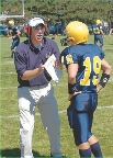 Photograph of a coach talking to a football player on the field