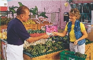 This woman is the first customer. She buys two heads of broccoli for $1.98.