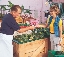 Photograph of a woman buying produce in a market