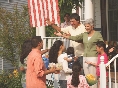 Photograph of two people greeting others on the steps of a home