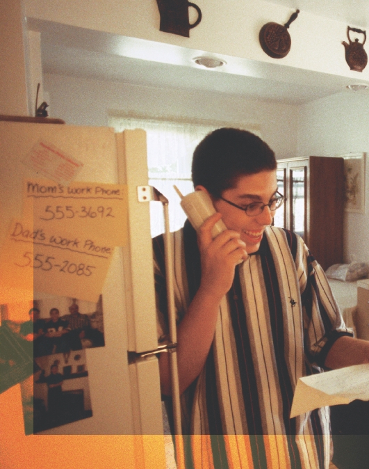 photograph of a teenage boy reading a letter and talking on the phone