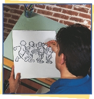 photograph of a man drawing sketches of cartoon characters on a pad