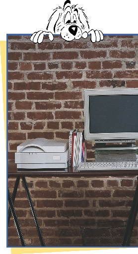 photograph of a desk with computer and cartoon character dog looking on