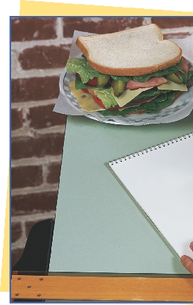 photograph of a sandwich on a table and a sketch pad