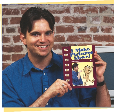 photograph of male artist holding a book titled “I Make Pictures Move”