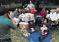 photograph of a family sitting on a lawn and chairs in a park-like setting