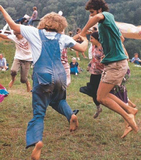 photograph of a group of people outdoors, several are dancing in a circle