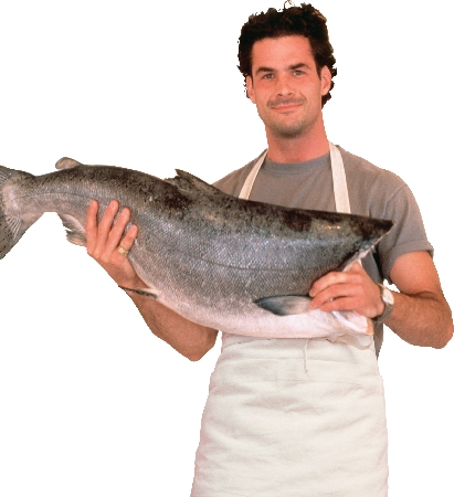 Photograph of a man who works at the fish market, holding up a large fish.