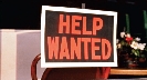 Photograph of a “help wanted” sign in the window of a restaurant.