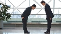 Photograph of two Japanese adult men bowing to each other.