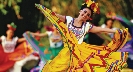 Photograph of woman in colorful ethnic costumes dancing.