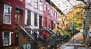 Photograph of a row of family homes along a tree-lined street in Boston.