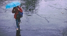 Photograph of a person walking with an umbrella on a rainy day