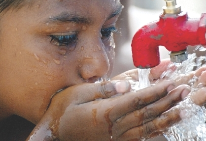 Everybody needs water, especially when it’s hot! This boy drinks water on a hot summer day.