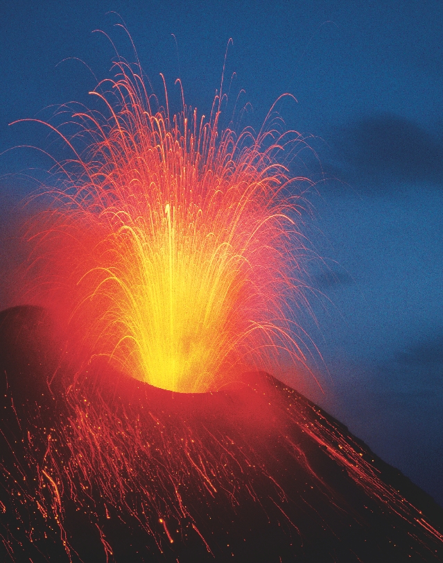 Photograph of red-hot lava thrown into air and flowing down the sides of a volcano