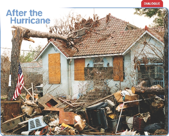 Photograph of a home destroyed by a tree which has fallen onto it and furniture, wood, and other items piled up in front of it brought there by floodwater