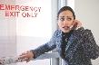 Photograph of a woman opening an emergency exit door in a hurry and speaking on a cell phone